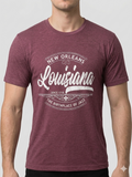 A man wearing a heathered maroon short-sleeve t-shirt with a distressed white graphic that reads 'New Orleans Louisiana The Birthplace of Jazz'.