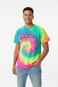 A man wearing a vibrant tie-dye t-shirt with a spiral pattern in green, yellow, pink, and blue, featuring the text 'NEW ORLEANS' printed across the chest. He is also wearing light-wash blue jeans, standing against a plain white studio background.