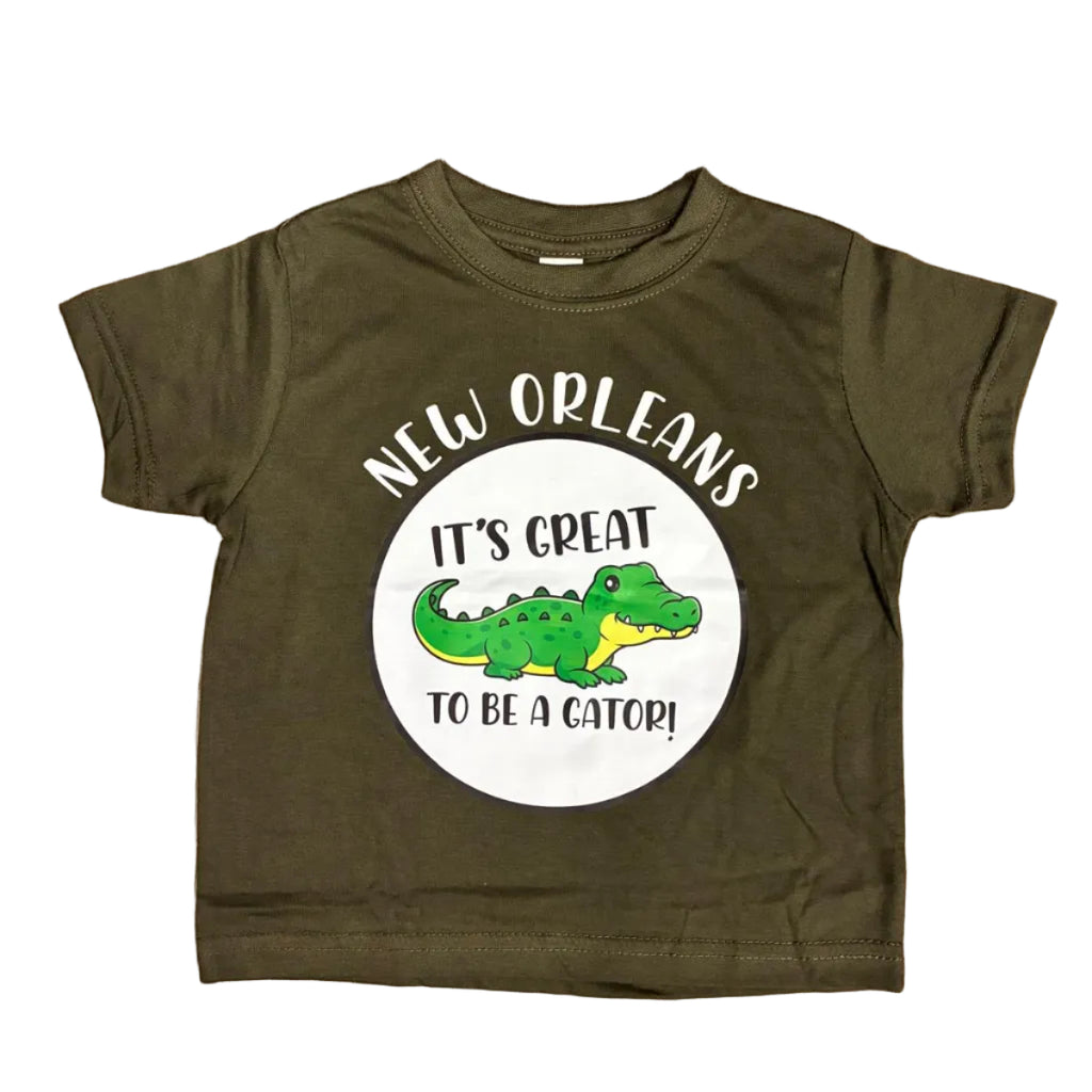 A toddler t-shirt with the Gator printed in the center of a circle with the words "It's Great to be a Gator!" and New Orleans above the circle was placed on a white backdrop.