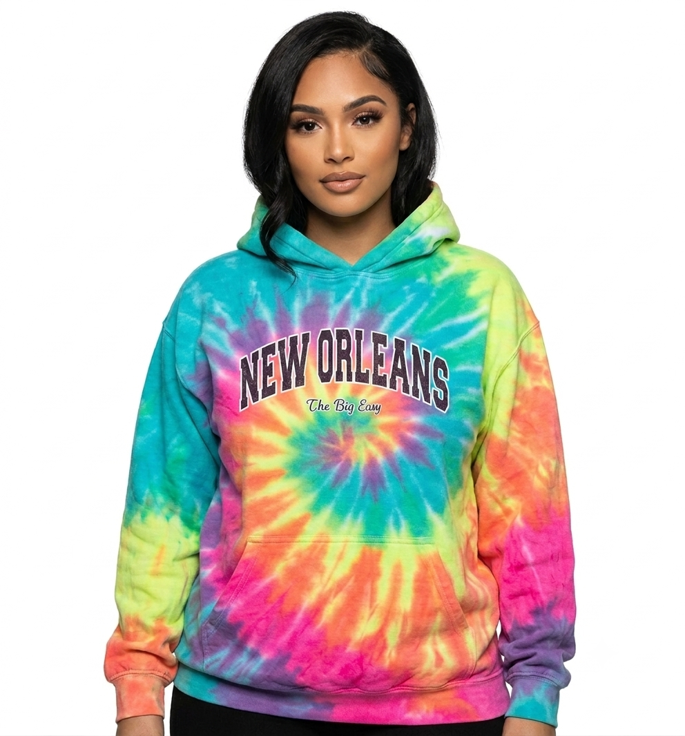 A woman modeling a vibrant tie-dye hoodie with a spiral pattern of green, blue, yellow, orange, and pink. The hoodie features 'NEW ORLEANS' printed in arched black letters with a white outline across the chest and 'The Big Easy' written underneath in script.