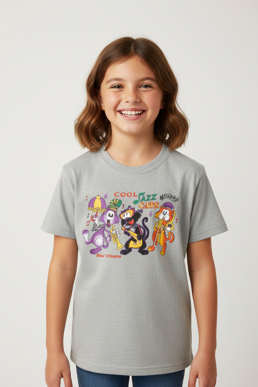 A smiling young girl with shoulder-length brown hair wearing a light gray heather graphic t-shirt. The shirt features a colorful cartoon print of Disney's New Orleans Jazz & Heritage Museum characters and the text 'COOL Jazz Club New Orleans'.