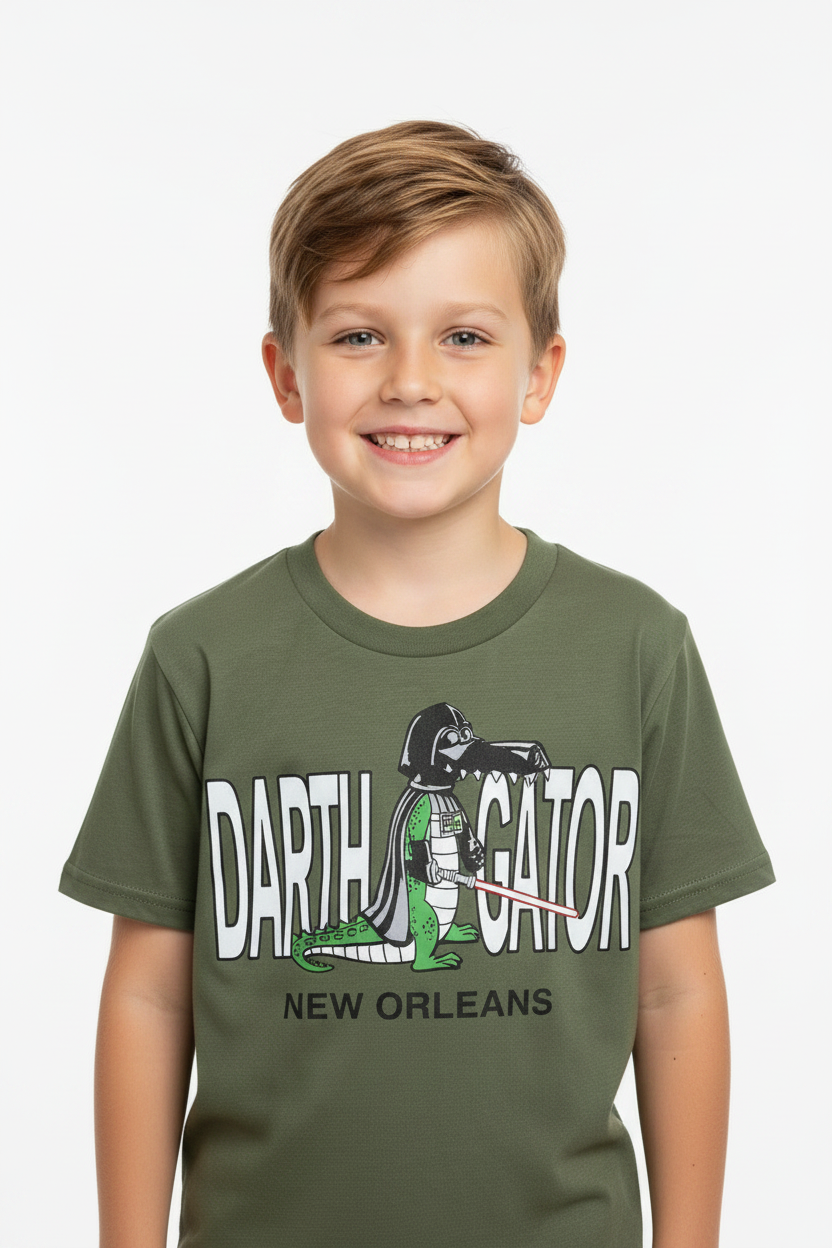 A smiling young boy wearing an olive green t-shirt with a graphic print of Darth Vader as a gator and the text 'DARTH VATOR NEW ORLEANS'.