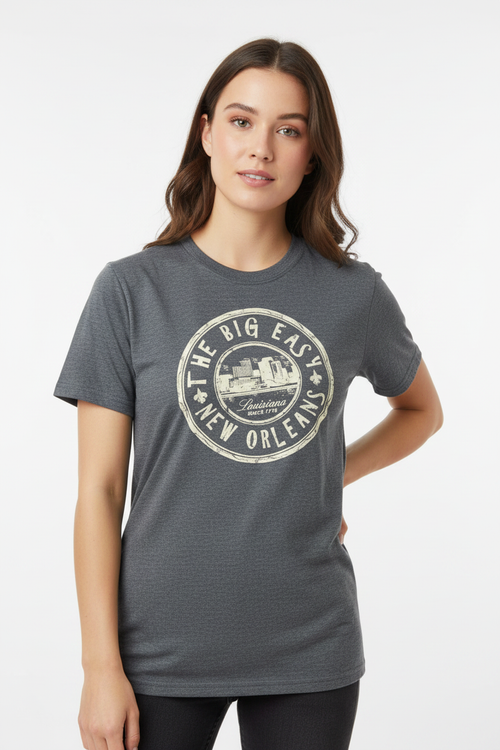 A woman wearing a dark heather gray t-shirt with a distressed white circular graphic that reads 'THE BIG EASY NEW ORLEANS'.