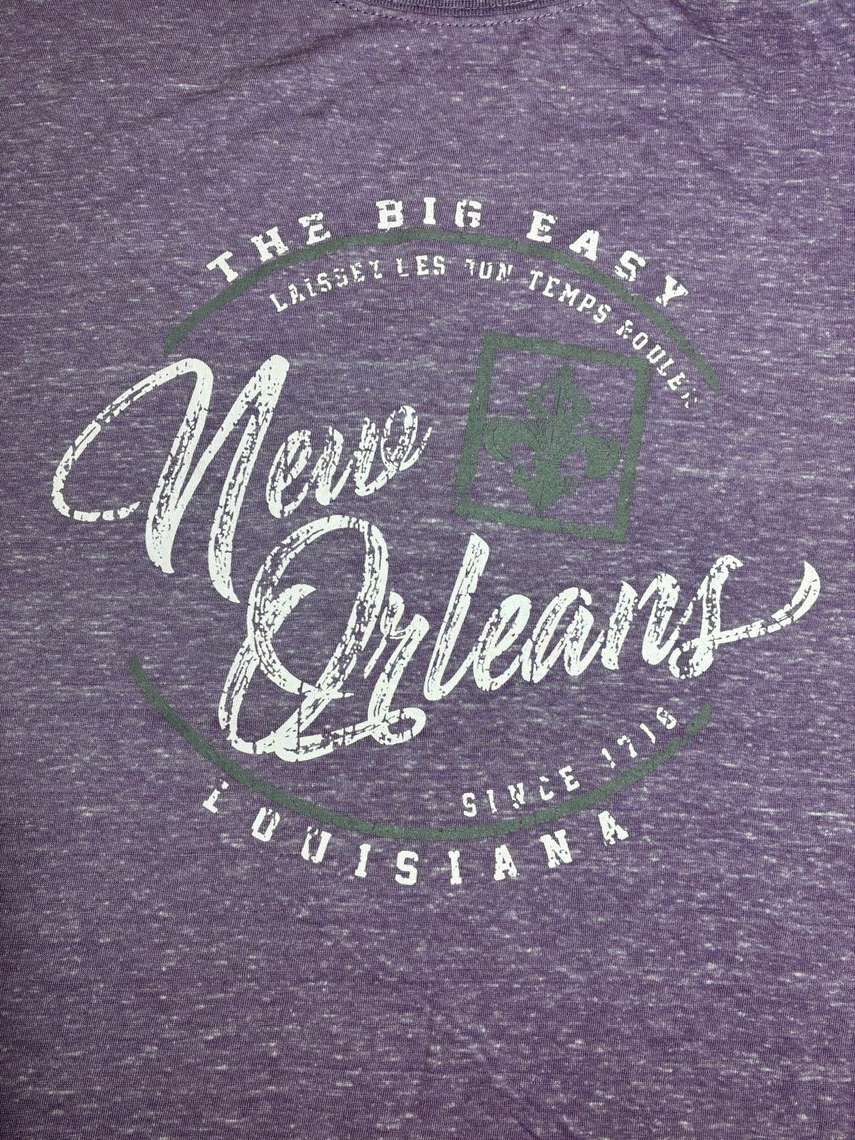 Close-up of heather purple t-shirt graphic featuring distressed white script 'New Orleans Louisiana Since 1718 The Big Easy' with fleur-de-lis detail in green"