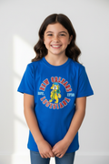 A young girl with long brown hair smiling, wearing a bright blue short-sleeve t-shirt with a 'New Orleans Louisiana 1795' graphic on the front, paired with blue jeans, set against a light gray background.