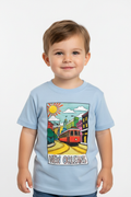 A young child wearing a light blue t-shirt with a colorful graphic of a New Orleans street scene featuring a red trolley and the text 'NEW ORLEANS'.