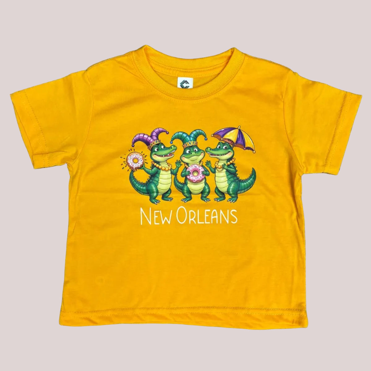 A toddler yellow short-sleeve t-shirt with a colorful graphic of three green alligators holding donuts and an umbrella, with the text 'New Orleans' printed below. 
